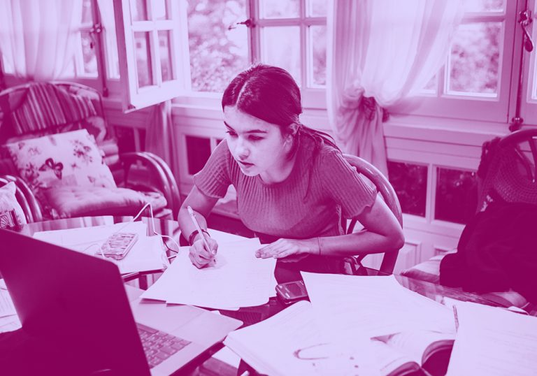 girl sitting at a desk doing her homework, with papers and laptop all around, purple filter.