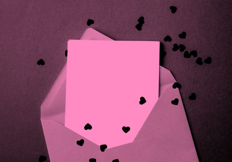 blank page in an envelope, heart confetti scattered around, pink filter.