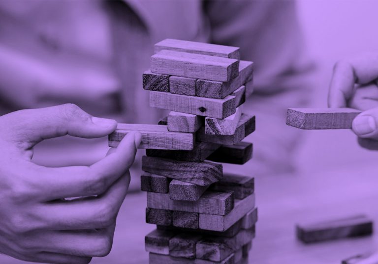 close up of two hands playing jenga, purple filter