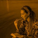 woman writing at the lake, orange filter