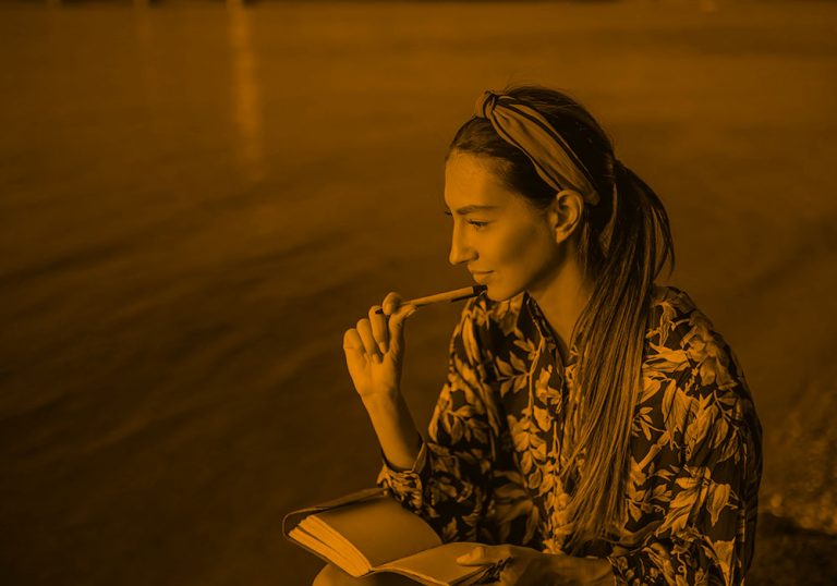 woman writing at the lake, orange filter