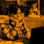 student at computer; orange filter